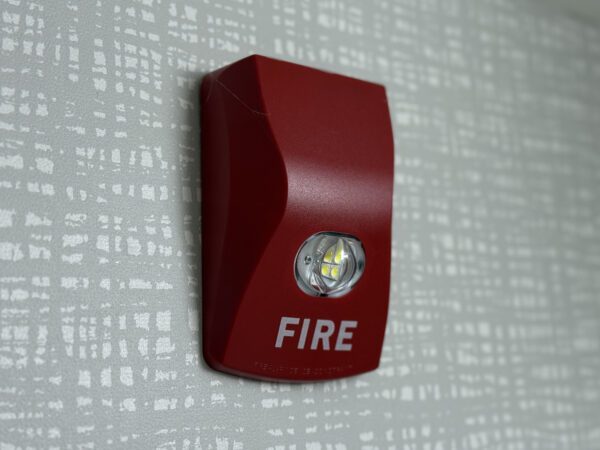 Red commercial fire alarm notification strobe and horn mounted on a wall